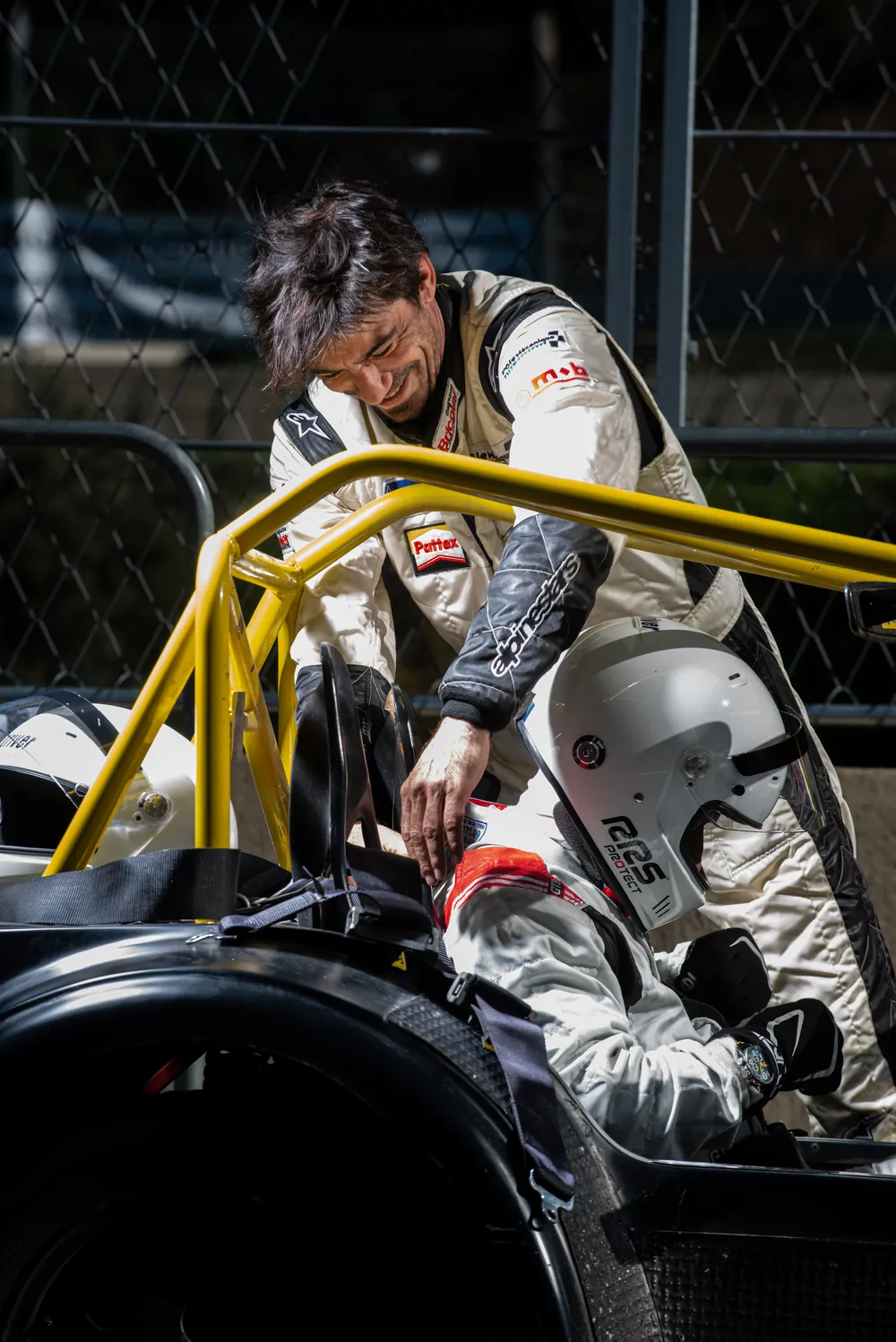 Robin Longechal, moniteur, se penche vers un élève casqué installé dans la Caterham avant de partir en piste