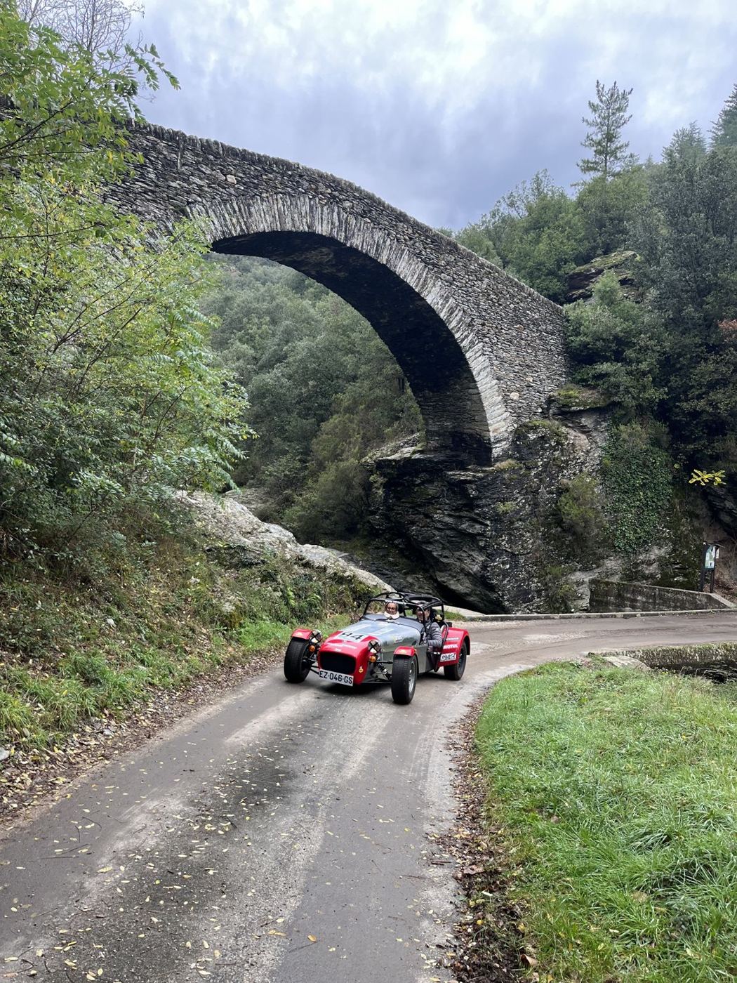 Caterham passant sous un pont de pierre dans les Cévennes
